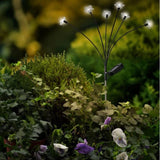 Ramo decorativo solare con fiori luminosi installato tra piante e fiori in un giardino