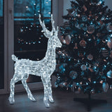 Renna 3D 105 cm in acrilico illuminata da LED bianchi all’interno di una casa, accanto a un albero di Natale decorato con luci e addobbi.