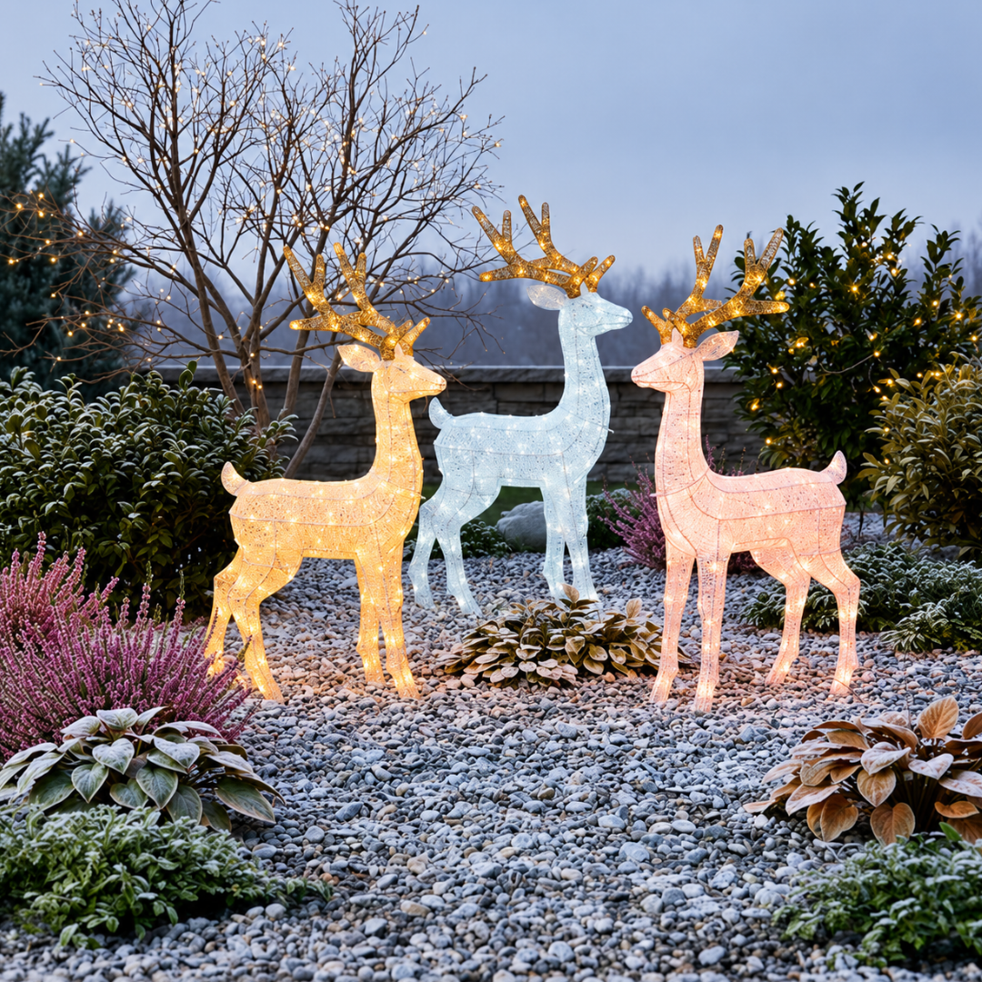 Tre renne natalizie luminose con corna dorate, ambientate in un giardino con piante e decorazioni luminose.