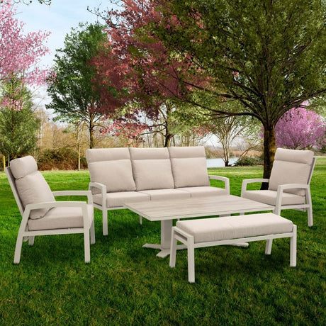 salotto clark con tavolo basso con attorno posti a sedere su panche e poltrone. Sullo sfondo un giardino 