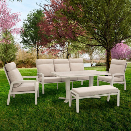 salotto clark con tavolo alto  con attorno posti a sedere su panche e poltrone. Sullo sfondo un giardino 