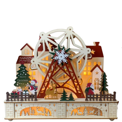 Scena natalizia in legno illuminata con ruota panoramica, casette con finestre luminose, alberi e figure di Babbo Natale e renne in un paesaggio festivo.