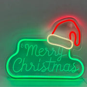 Decorazione luminosa natalizia con scritta verde Merry Christmas e cappello di Babbo Natale rosso in stile neon LED.