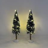 Due alberi natalizi decorativi con neve artificiale e micro LED caldi accesi, su base bianca.
