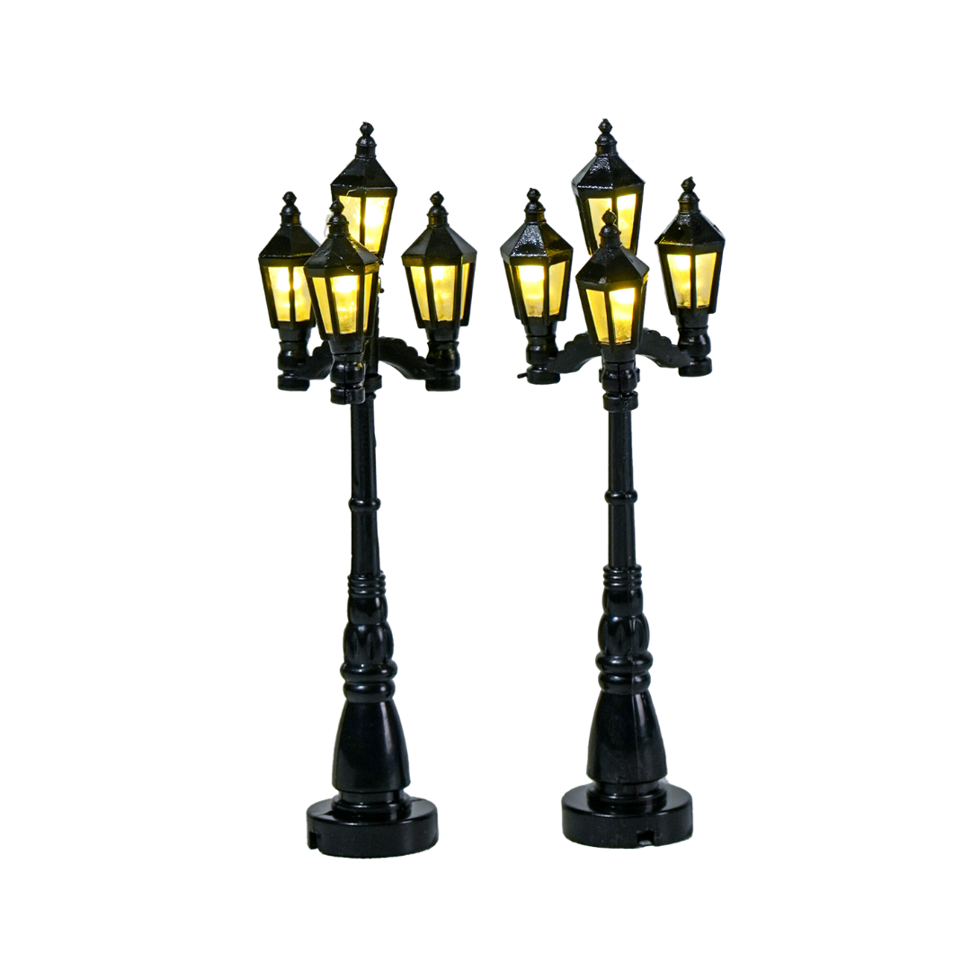 Set di 2 lampioni neri in stile classico per villaggio natalizio, ciascuno con quattro lanterne illuminate a luce calda