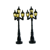 Set di 2 lampioni neri in stile classico per villaggio natalizio, ciascuno con quattro lanterne illuminate a luce calda