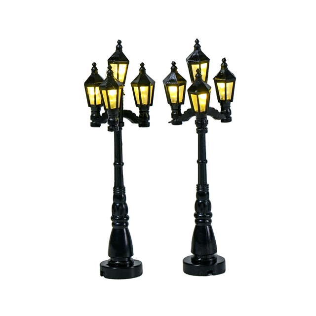 Set di 2 lampioni neri in stile classico per villaggio natalizio, ciascuno con quattro lanterne illuminate a luce calda