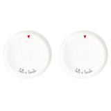 Set di due piatti piani in grès con scritta nera "tutti a tavola" e cuoricino rosso.
