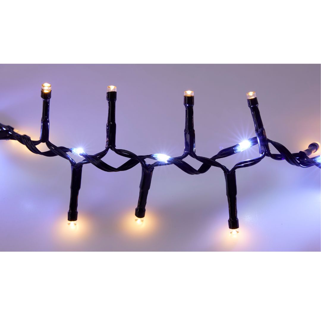 Dettaglio di catena luminosa 1410 LED con cavo nero e luci alternate bianco caldo e bianco freddo, accese e intrecciate tra loro su sfondo neutro.