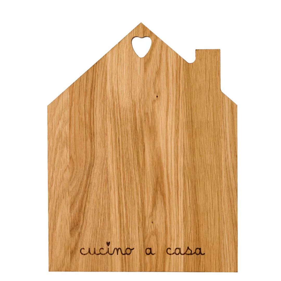 Tagliere in legno con sagoma a forma di casetta e la scritta "cucino a casa" incisa.