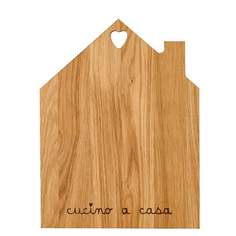 Tagliere in legno con sagoma a forma di casetta e la scritta "cucino a casa" incisa.