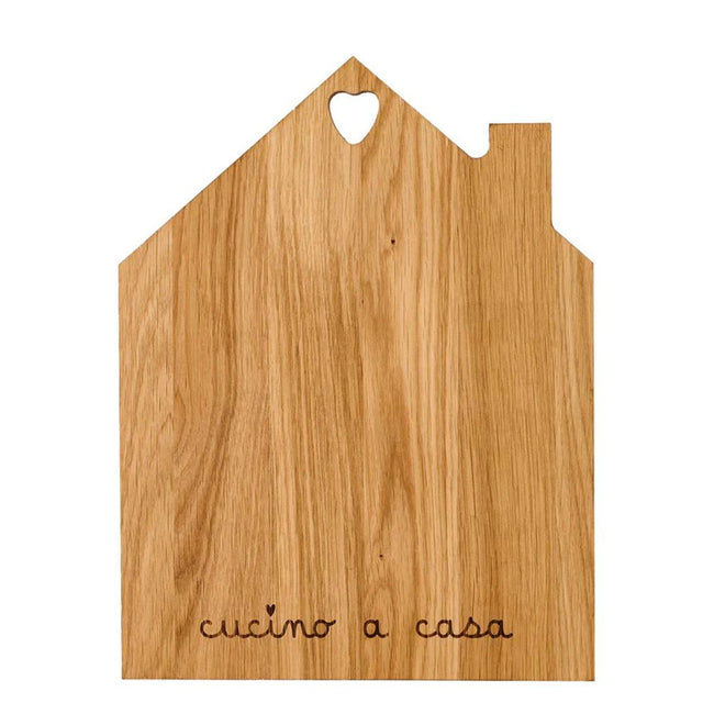 Tagliere in legno con sagoma a forma di casetta e la scritta "cucino a casa" incisa.