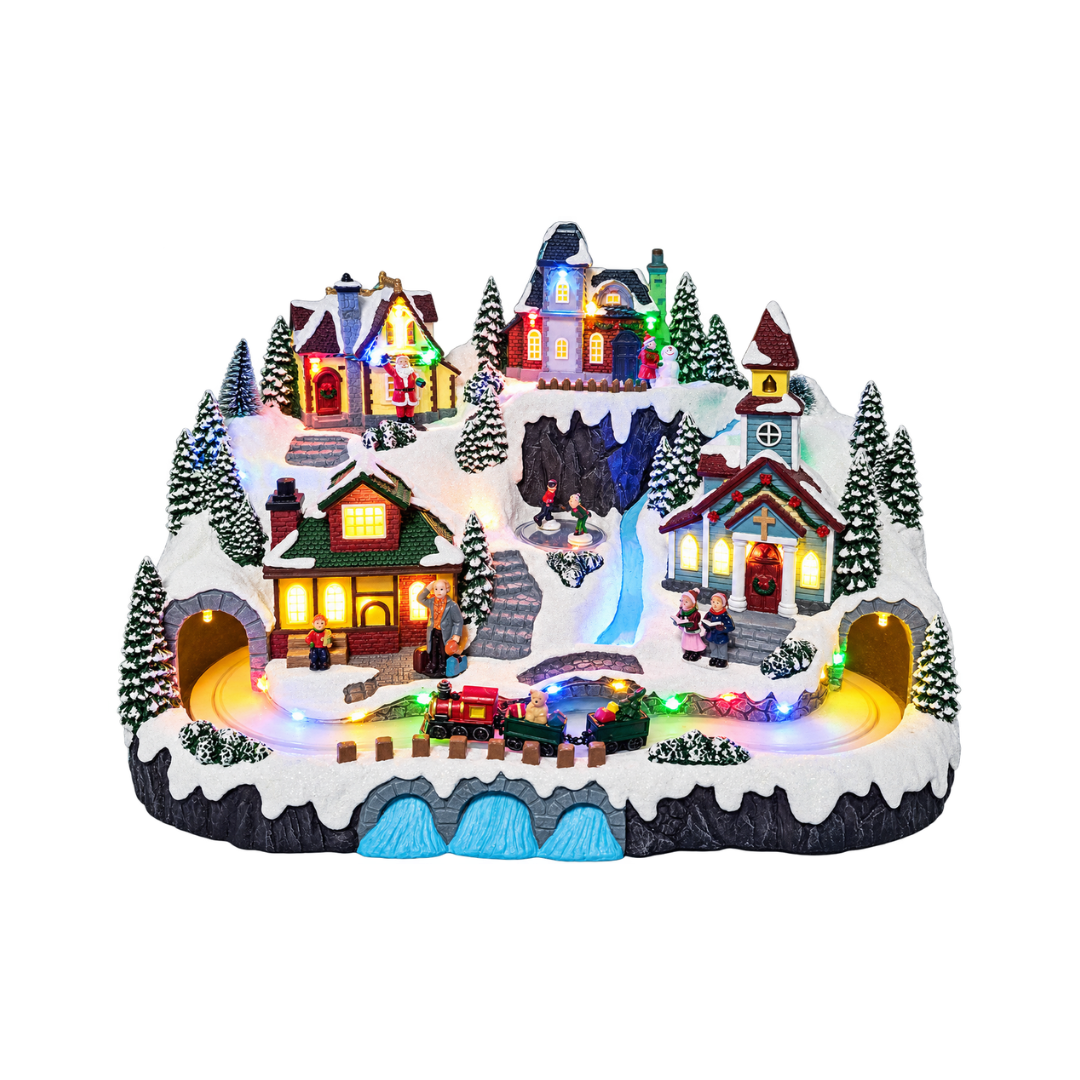 Villaggio natalizio innevato e illuminato con case, chiesa, personaggi e alberi, attraversato da un trenino tra due gallerie e decorato con luci LED multicolore