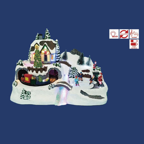 Villaggio natalizio in miniatura con casa illuminata, albero decorato, trenino che passa in galleria e figure di persone che pattinano sulla neve con Babbo Natale su sfondo blu.