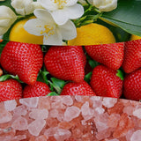 Collage con fiori bianchi di agrumi, fragole e cristalli di sale rosa che richiama la profumazione della candela.