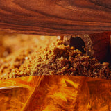 Collage con legno scuro, zucchero di canna e ambra che richiama la profumazione della candela.