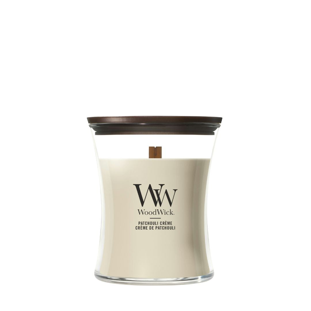 Candela WoodWick Patchouli Crème media in vaso di vetro con coperchio in legno.