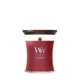 Candela WoodWick Spiced Blackberry media in vaso di vetro con coperchio in legno.