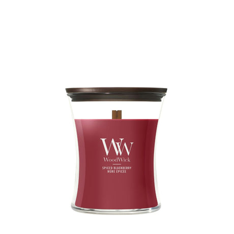 Candela WoodWick Spiced Blackberry media in vaso di vetro con coperchio in legno.