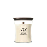 Candela WoodWick Vanilla & Sea Salt media in vaso di vetro con coperchio in legno.