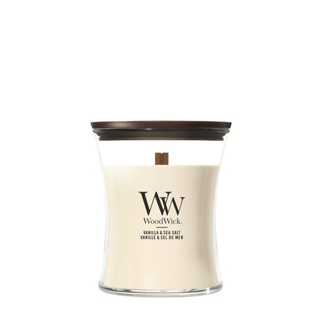 Candela WoodWick Vanilla & Sea Salt media in vaso di vetro con coperchio in legno.