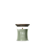 Candela WoodWick Verdant Fig piccola in vaso di vetro con coperchio in legno.