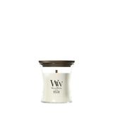 Candela WoodWick White Teak piccola in vaso di vetro con coperchio in legno.