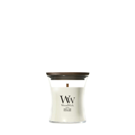 Candela WoodWick White Teak piccola in vaso di vetro con coperchio in legno.